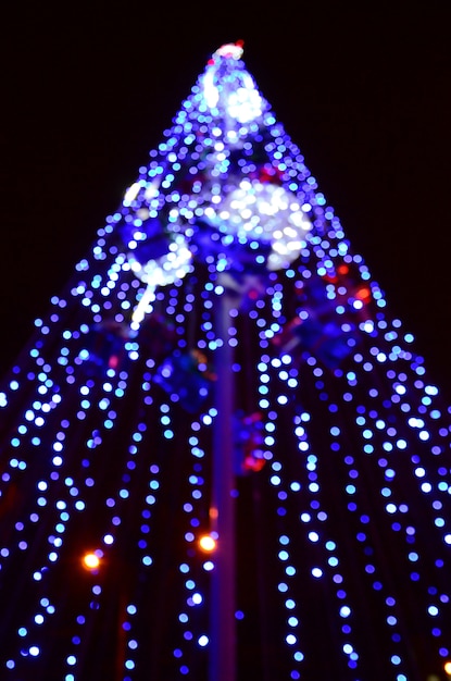 Fragmento borroso del árbol de año nuevo. Montones de luces redondas en azul.