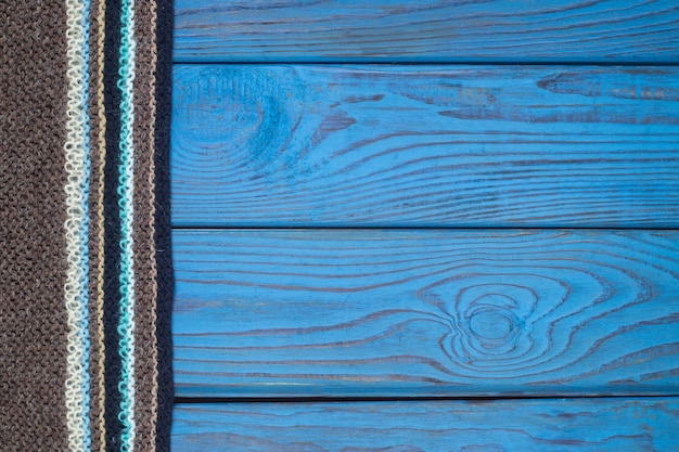 Foto fragmento de una bufanda tejida sobre una superficie de madera azul