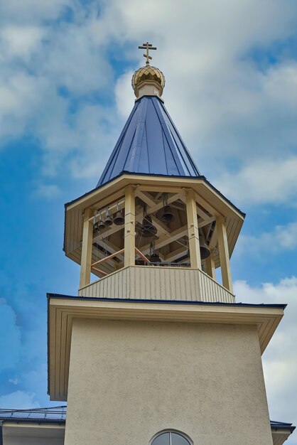 Fragmento del campanario de una iglesia cristiana con techo azul. Campanario de la iglesia contra el cielo