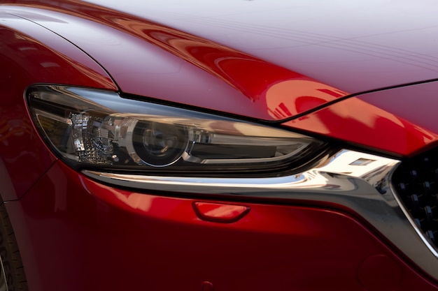 Fragmento de un coche rojo moderno, faro y parachoques. De cerca