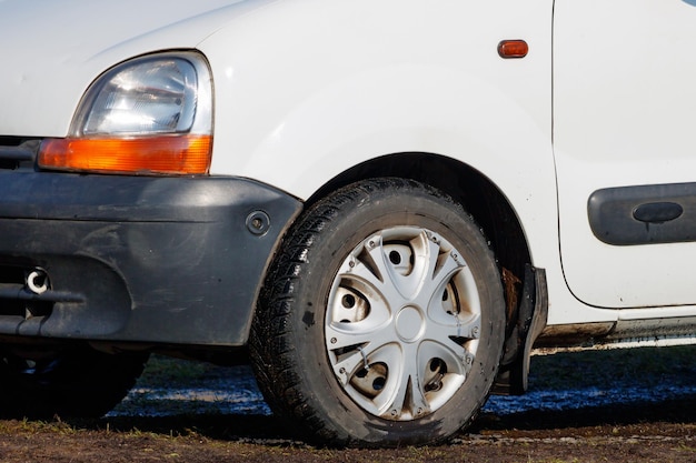 Fragmento de carro velho com farol danificado em pé na lama