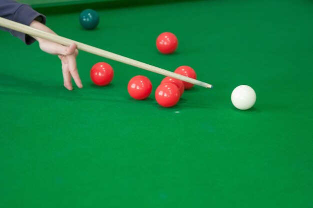 Mão do homem jogando sinuca no bar com bola de snooker