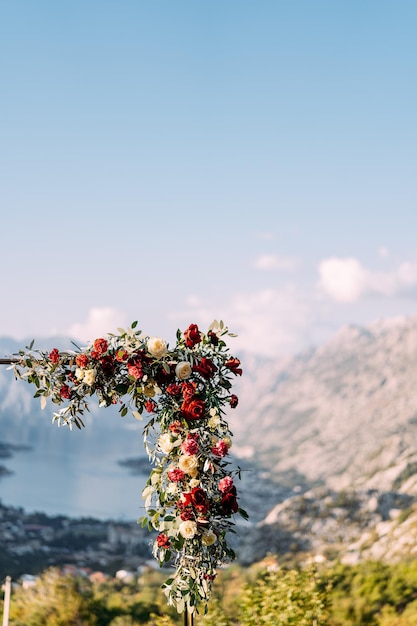 Fragmento de um arco de casamento de metal decorado com flores coloridas em um fundo de montanhas