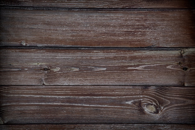 Fragmento de uma cerca feita de velhas tábuas de madeira com resquícios de tinta e textura natural de pregos