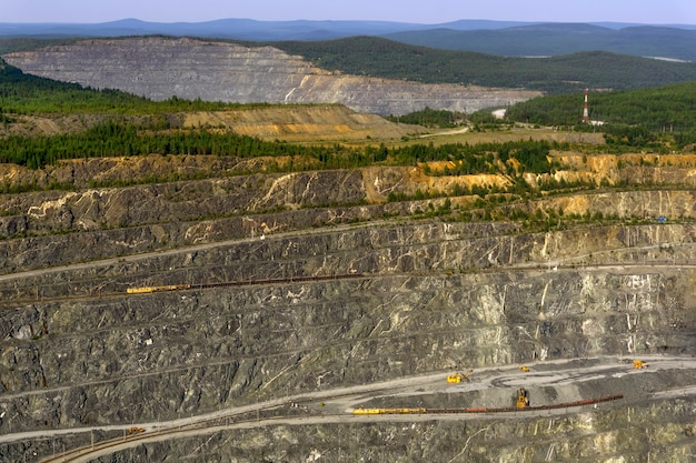 Fragmento de uma enorme carreira de mineração com escavadeiras, caminhões basculantes e outros equipamentos de pedreira