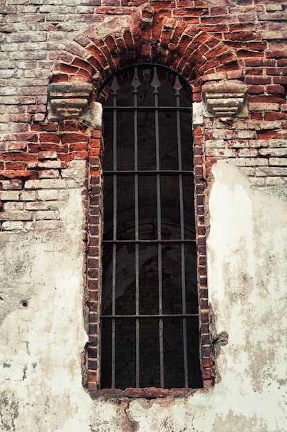 Fragmento de uma parede de igreja velha com uma janela e uma treliça.