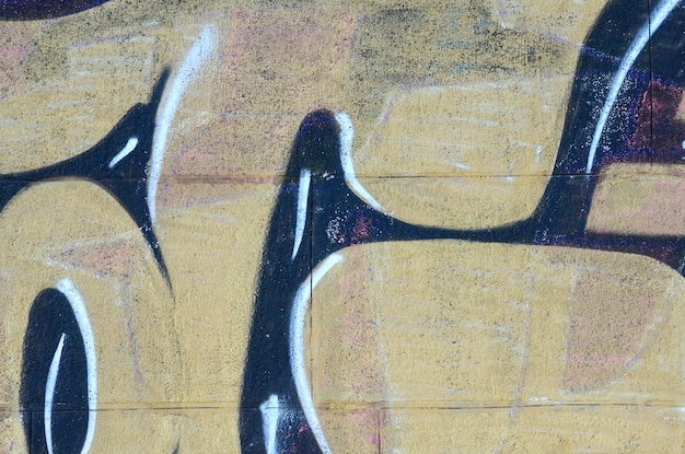 Foto fragmento de dibujos de graffiti la vieja pared decorada con manchas de pintura en el estilo de la cultura del arte callejero textura de fondo de colores en tonos cálidos