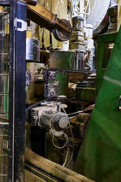 Foto fragmento do interior da oficina de uma moderna serraria com equipamentos recobertos por uma camada de serragem