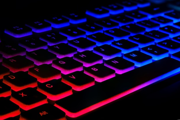 Fragmento do teclado do jogo com luz de fundo colorida sobre fundo preto Aproximação do teclado do computador