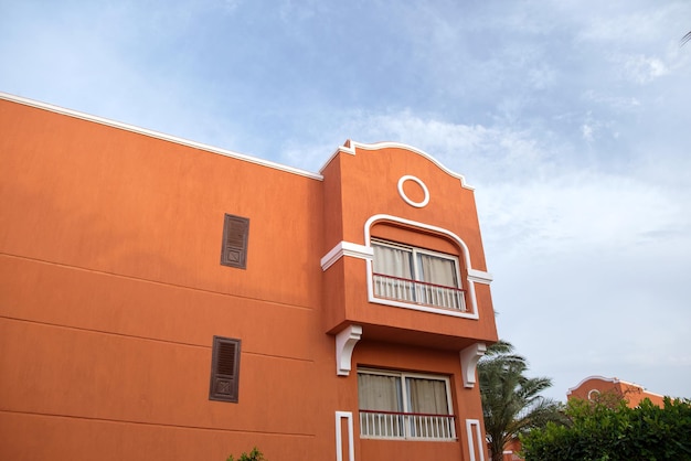 Fragmento del exterior del hotel resort de ladrillo rojo con palmeras bajo el cielo azul de verano