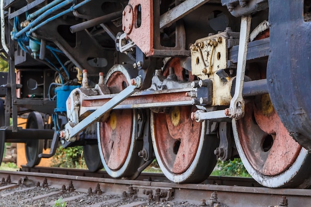 Foto fragmento de una vieja locomotora oxidada de pie sobre las vías del tren