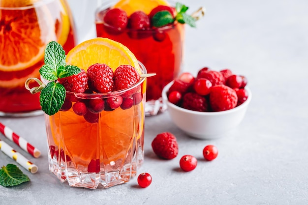 Framboesa Cranberry Sangria Punch ou Mojito em copos com fatias de laranja e hortelã