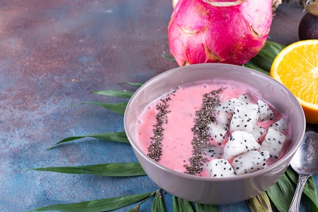 Framboesas vermelhas ou rosa smoothie tigelas cobertas com sementes frescas de pitaya e chia na palma da mão sobre fundo de pedra, cópia espaço