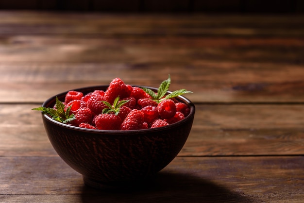 Framboesas vermelhas suculentas frescas deliciosas sobre uma mesa escura. Bagas e frutas sazonais