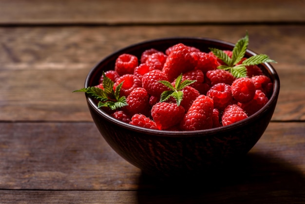 Framboesas vermelhas suculentas frescas deliciosas sobre uma mesa escura. Bagas e frutas sazonais