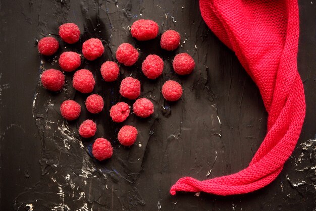 Frambuesa fresca con servilleta rosa sobre fondo negro. Corazón rojo - día de San Valentín y amistad