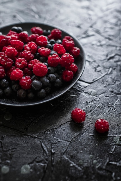 Frambuesas y arándanos, sobre un fondo negro, frutos del bosque