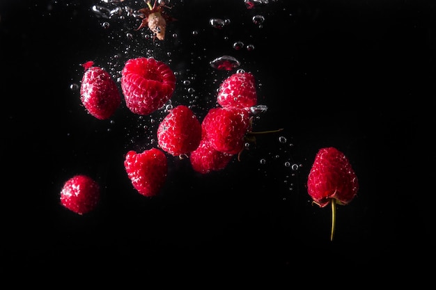 Frambuesas cayendo en el agua.