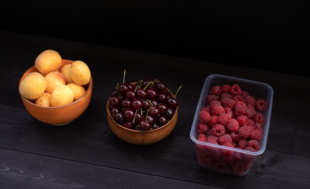 Frambuesas cerezas y albaricoques en madera