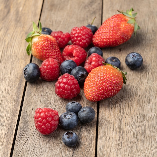 Frambuesas fresas y arándanos sobre mesa de madera