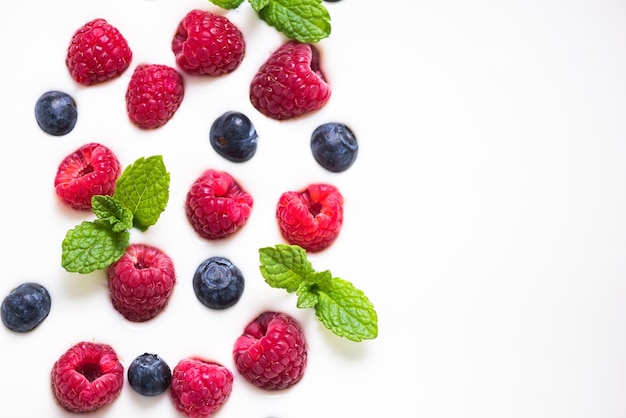 Frambuesas frescas y arándanos con menta sobre fondo de yogur