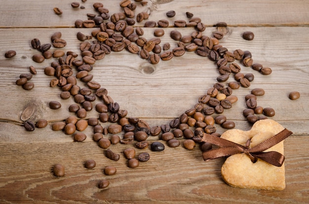 Frame- coração de grãos de café e cookies-coração relacionados juntos na mesa de madeira