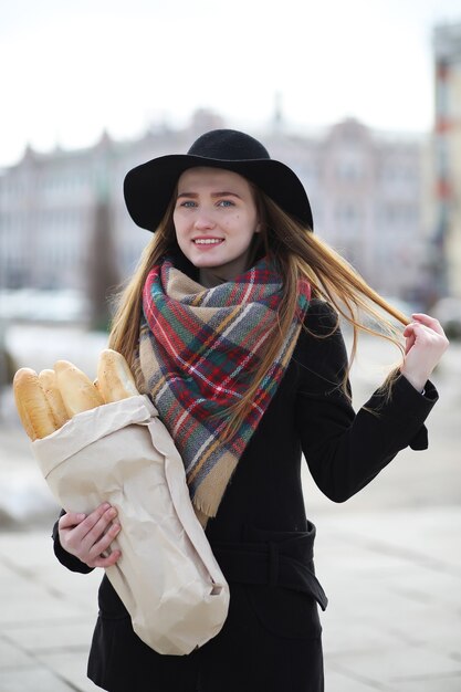 Foto francesa com baguetes na sacola saindo da loja