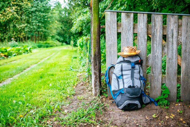 Francia, Estrasburgo, mochila de viaje y sombrero de paja delante de una valla de madera en el camino