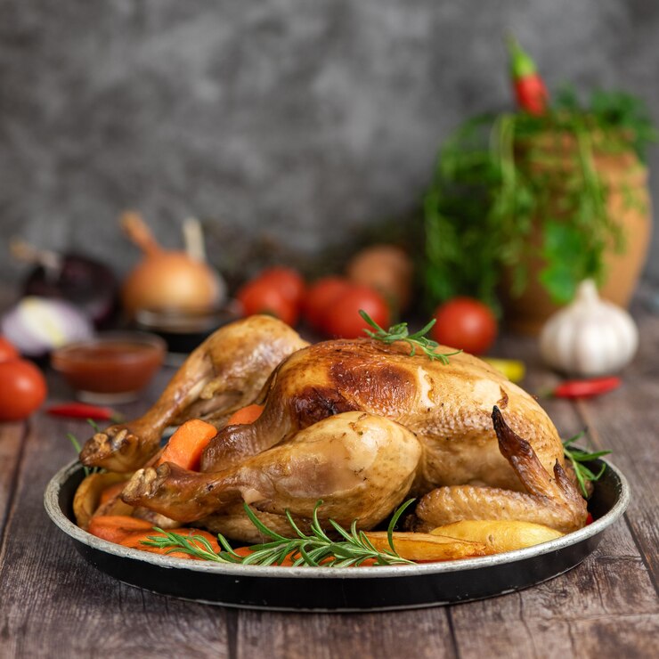Foto frango assado, batatas e legumes no prato em madeira escura. vista lateral.