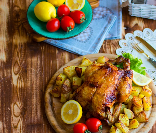 Frango assado caseiro com limão e batatas em um fundo de madeira