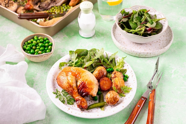 Frango assado com batatas e salada em um fundo verde