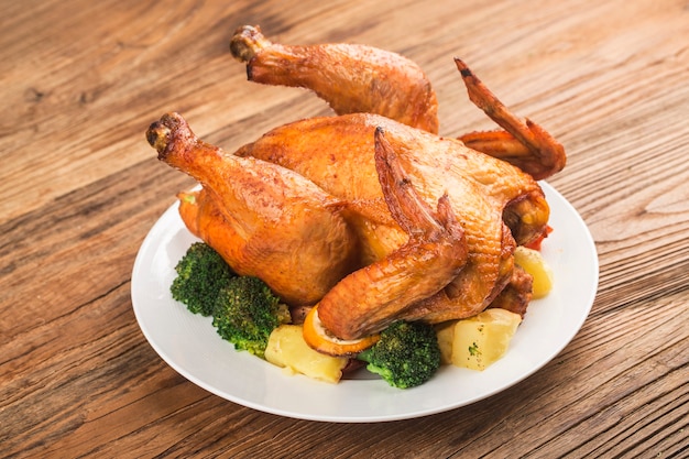 Frango assado com legumes na mesa de madeira