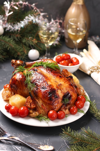 Frango assado com mel, molho de soja, cebola e alho, servido com batatas e tomate cereja, fundo de natal, orientação vertical, closeup