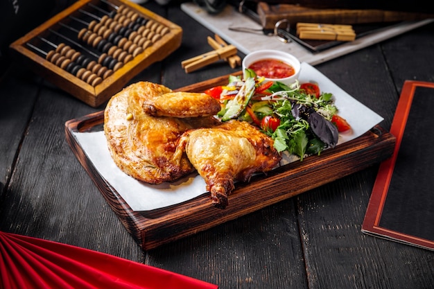 Frango assado com molho e verduras na tábua de madeira