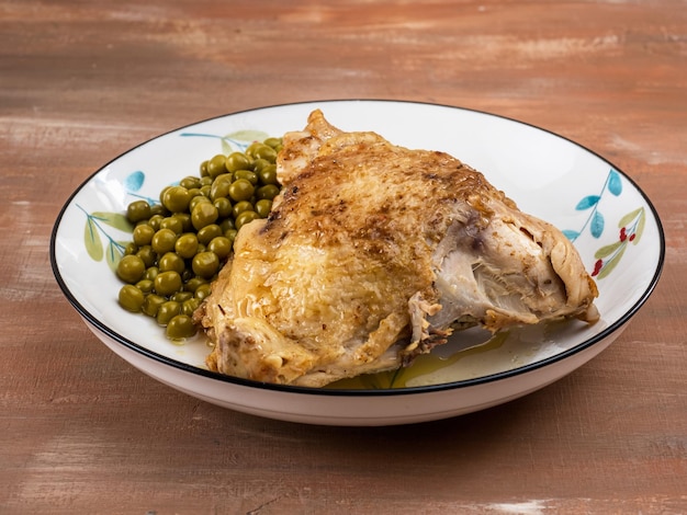 Frango assado e ervilhas enlatadas verdes e num prato com um padrão