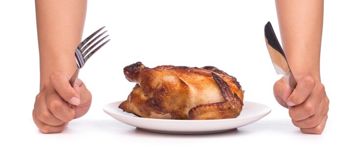 Foto frango assado sendo cortado por garfo e faca em um prato isolado no fundo branco