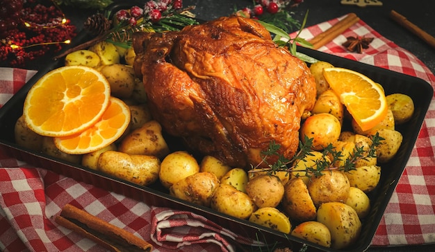 Frango com batatas ervas laranja e paus de canela em uma assadeira em um guardanapo de cozinha