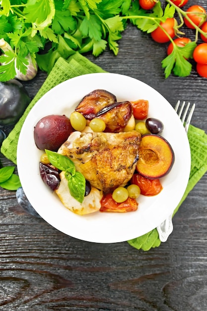 Frango com frutas e tomates no prato no topo da placa escura