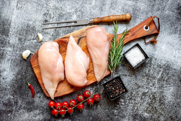 Frango cru em uma tábua com especiarias e ervas.