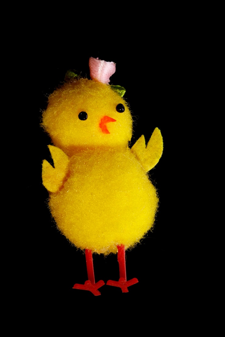 Foto frango de brinquedo isolado no fundo preto. galinha amarela engraçada. foto de alta qualidade