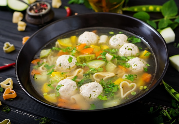 Frango e sopa de legumes com almôndegas, abobrinha e macarrão.