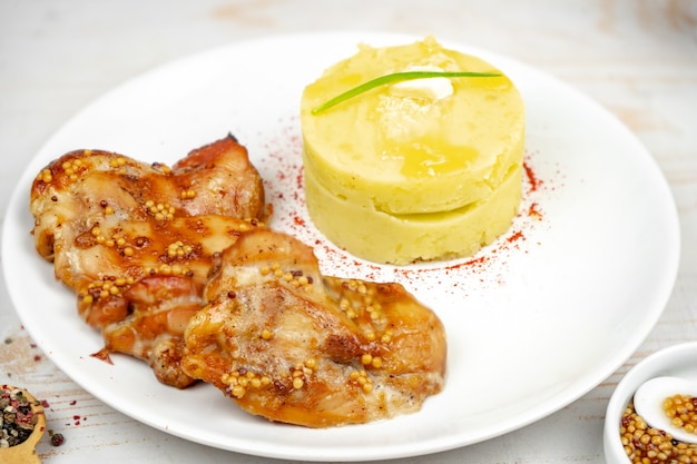Foto frango frito com molho de mostarda e mel com purê de batata no prato branco