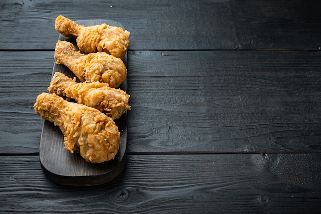 Frango frito crocante corta na mesa de madeira preta, com espaço de cópia.