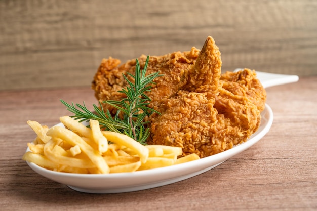 Frango frito e batata frita com folha de alecrim Junk food de alta caloria servido na chapa branca