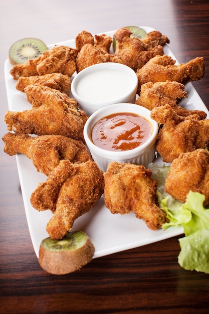 Frango frito e crocante de coxinha com dois tipos de molho na mesa de madeira