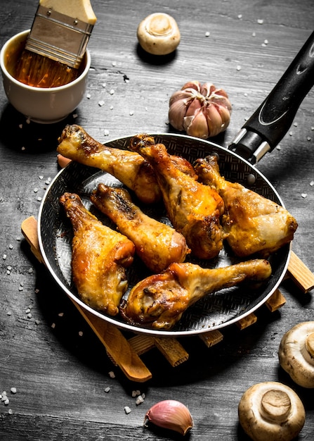 Frango frito em uma panela com cogumelos, alho e molho de tomate