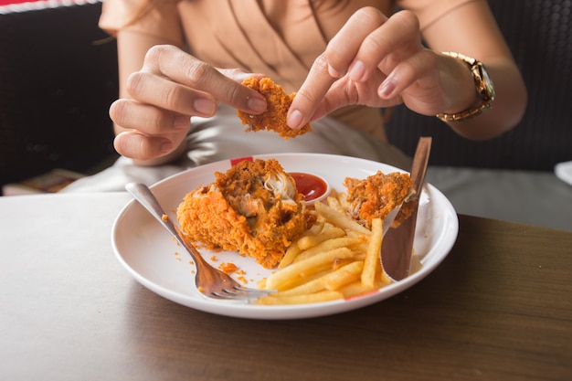 Foto frango frito no foco de seleção de mão de mulher jovem