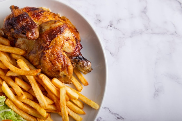 Frango grelhado com batatas fritas e salada em uma mesa de mármore. Vista superior com espaço de cópia.