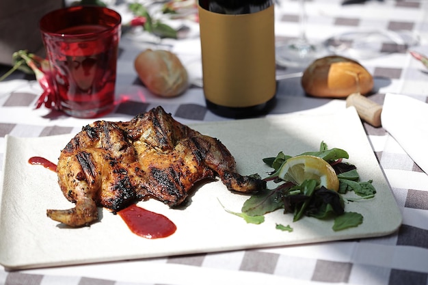 Frango grelhado com legumes e garrafa de vinho no fundo