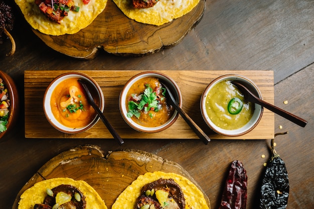 Frango grelhado e foie gras tacos servido na tábua de madeira com molhos diferentes.